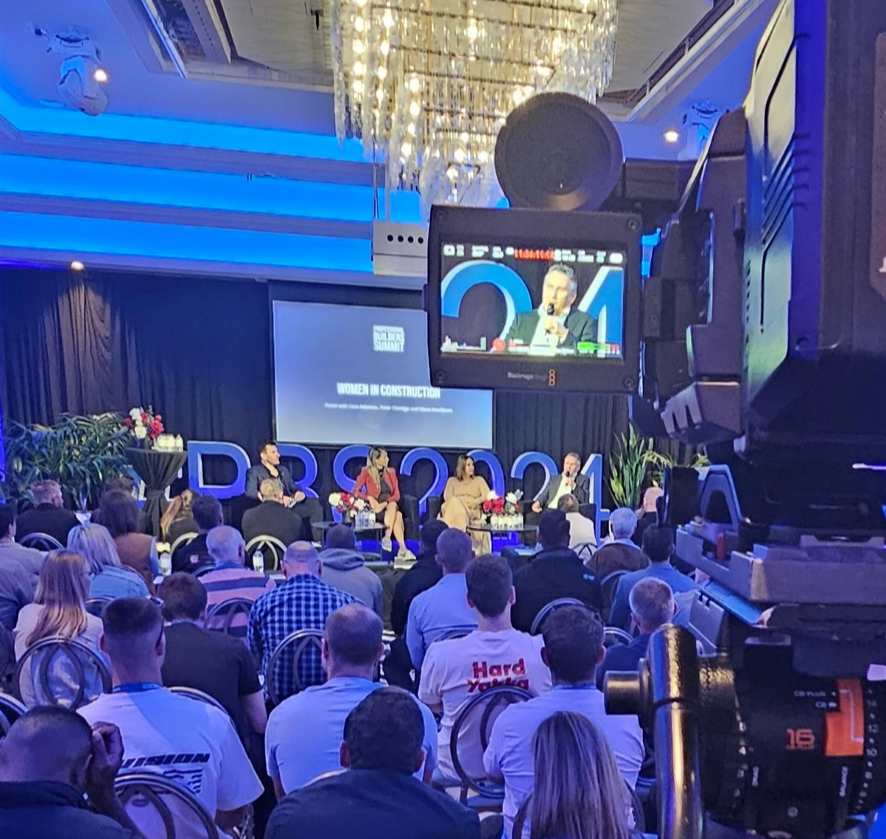 Conference audience facing a stage with a large screen