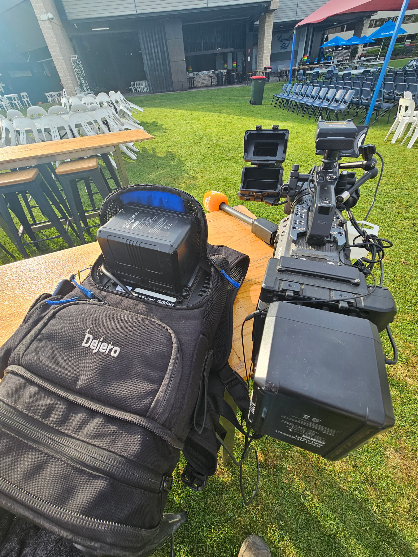 A DEJERO bonded transmitter beside a broadcast camera on grass