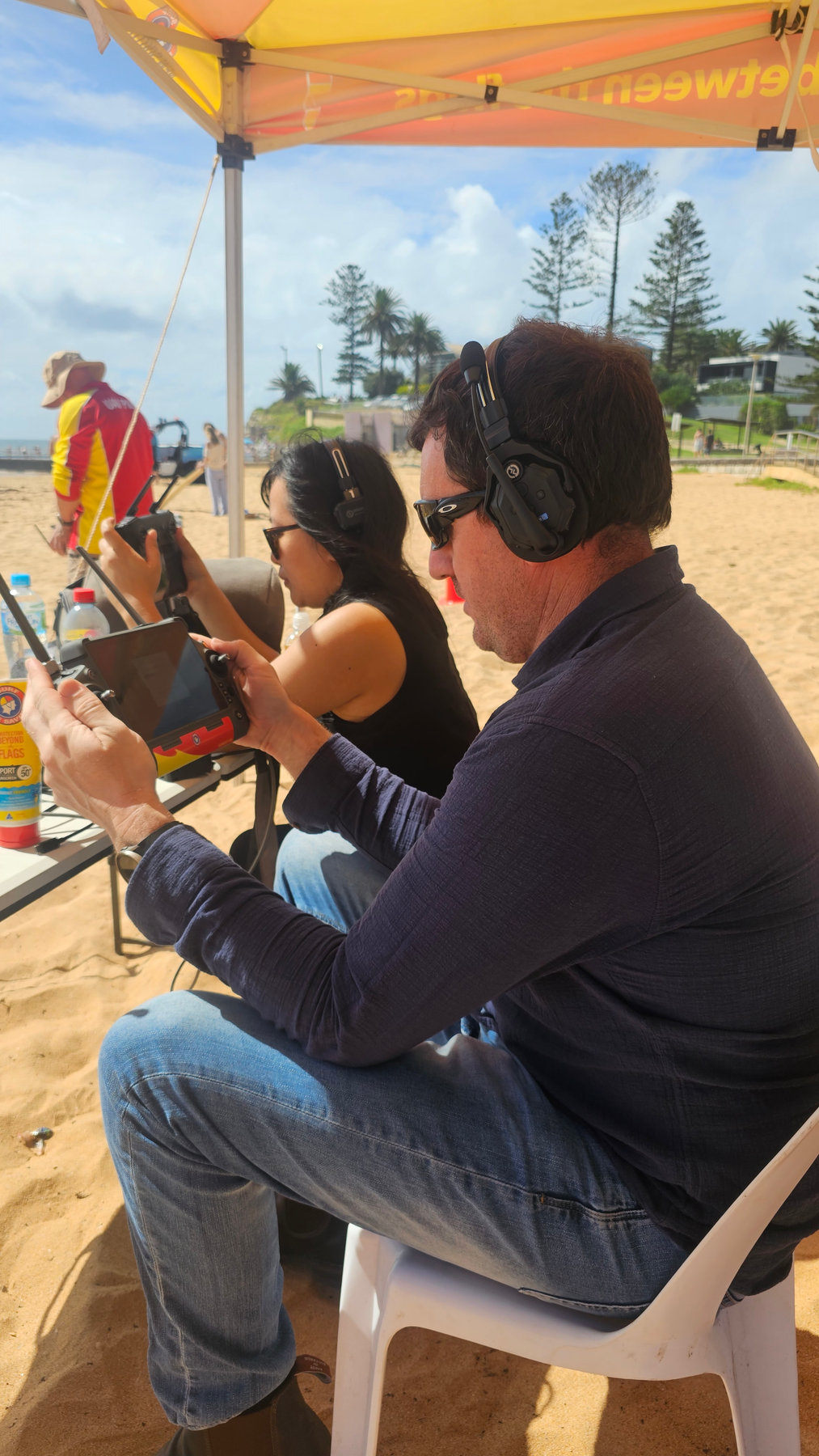 Evan and a colleague with drone controllers on a beach for a live broadcast