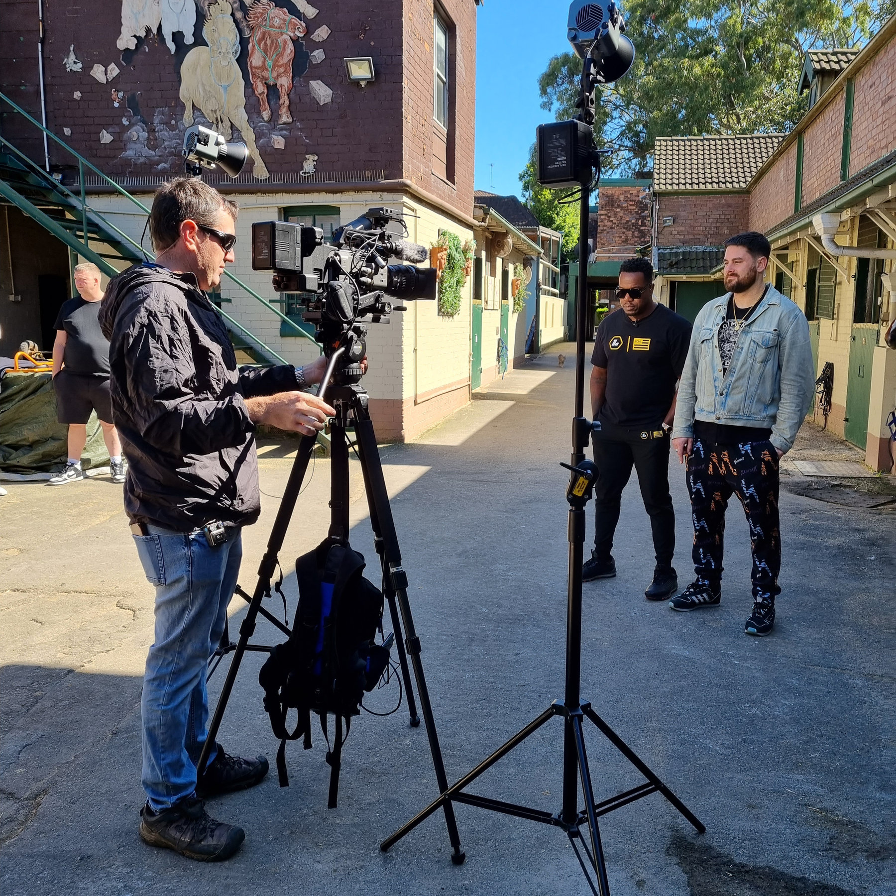 Evan operating a camera in a laneway with two talent