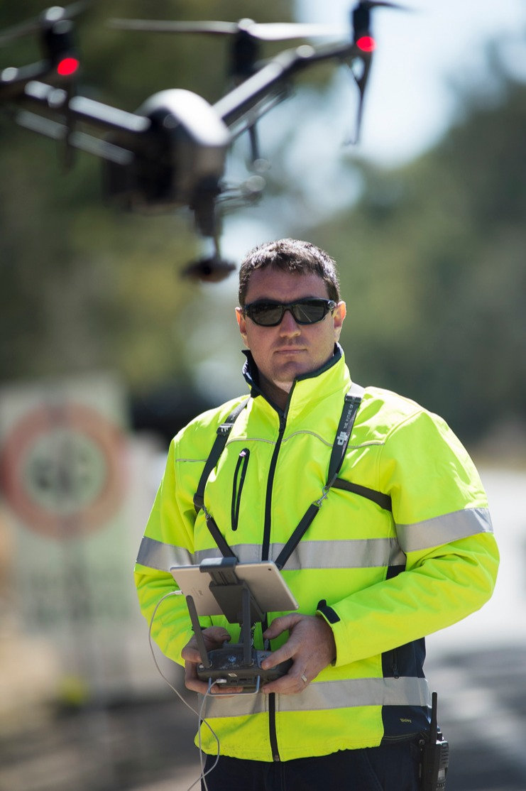 Evan in hi-vis holding a drone controller on a work site