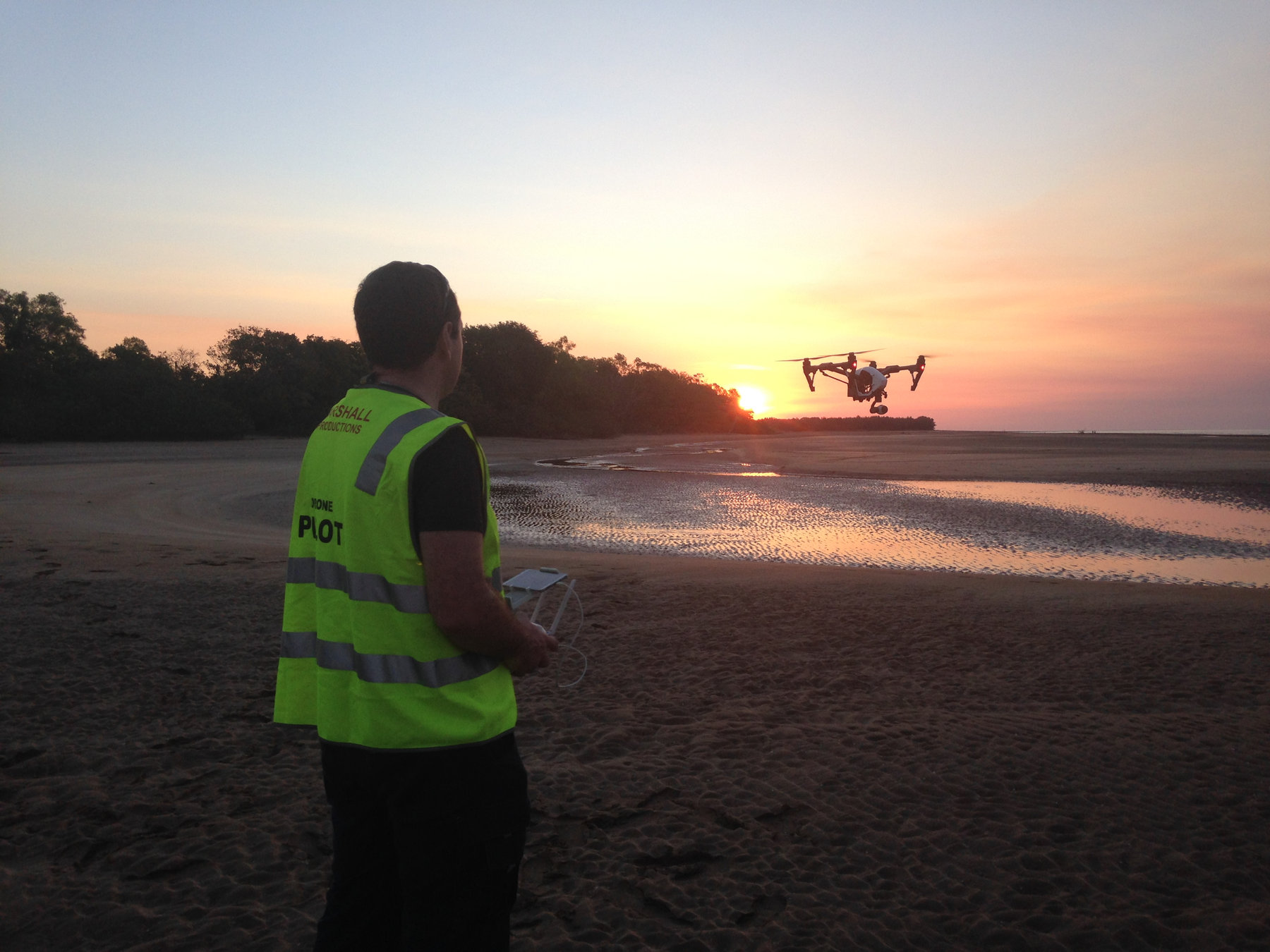 Evan Zell in a drone pilot vest flying a DJI Inspire at sunset on a beach