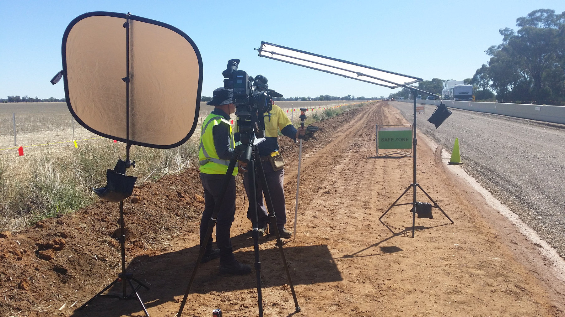Evan in hi-vis with a camera on a tripod beside a regional road