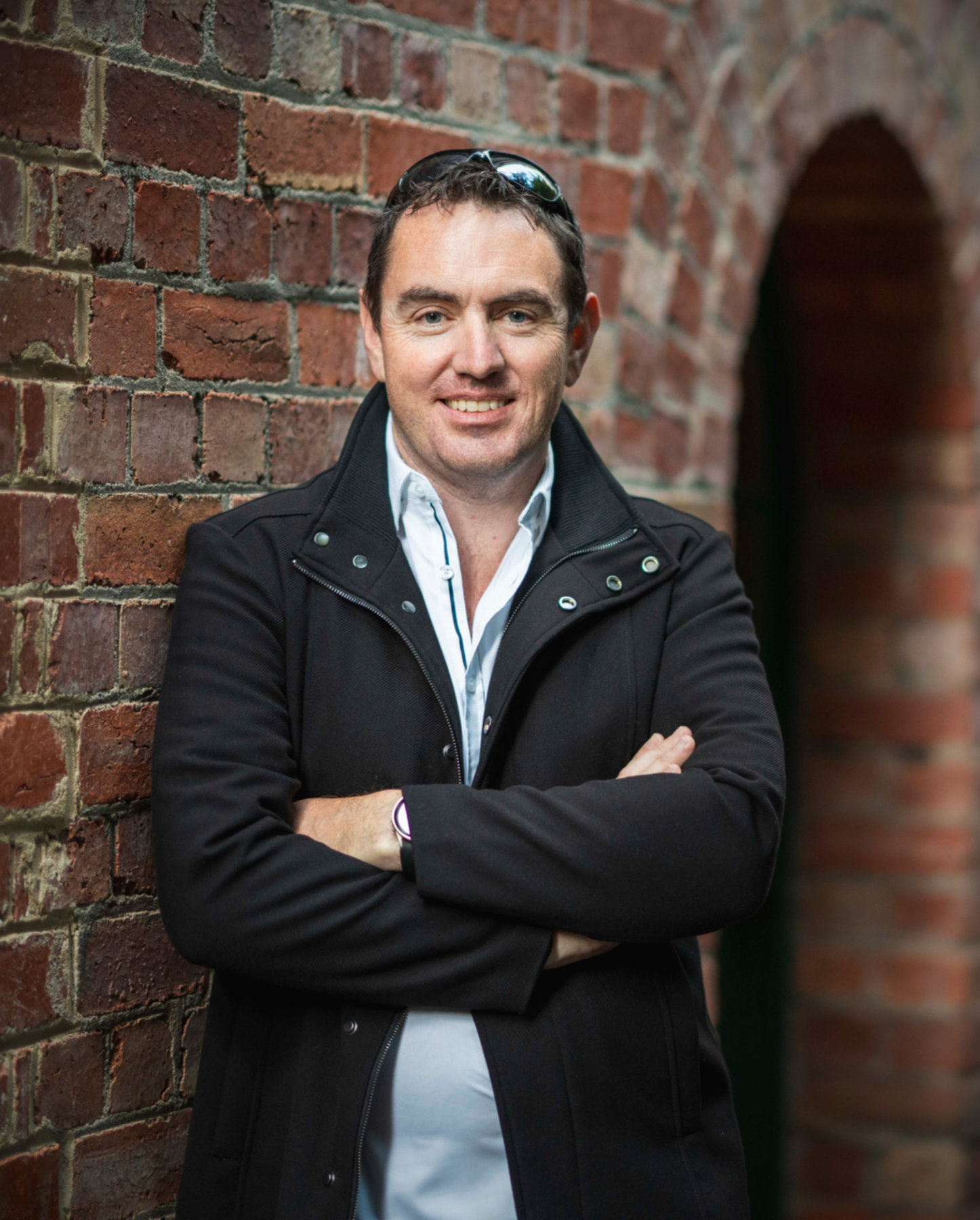 Evan Zell, portrait against a brick archway