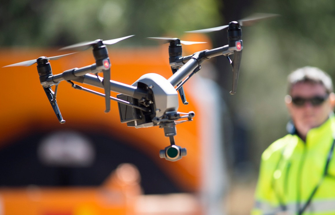 A DJI Inspire drone in flight against an orange background
