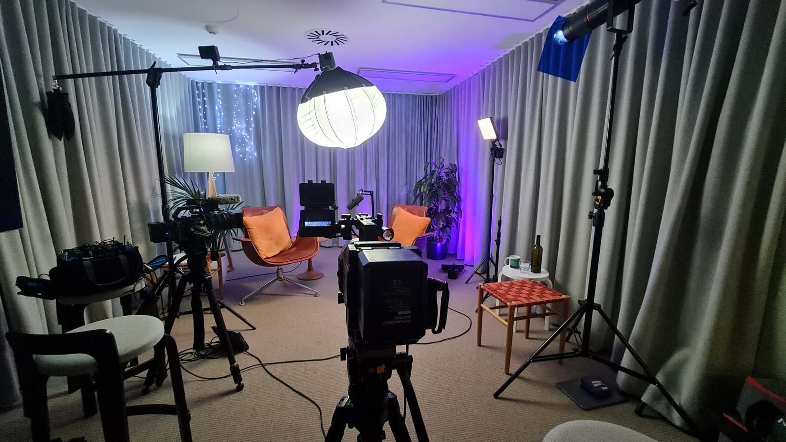 A podcast set lit with a round softbox and pink practicals