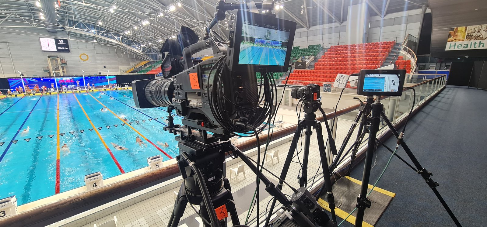 Broadcast camera on a tripod beside the pitch at a stadium