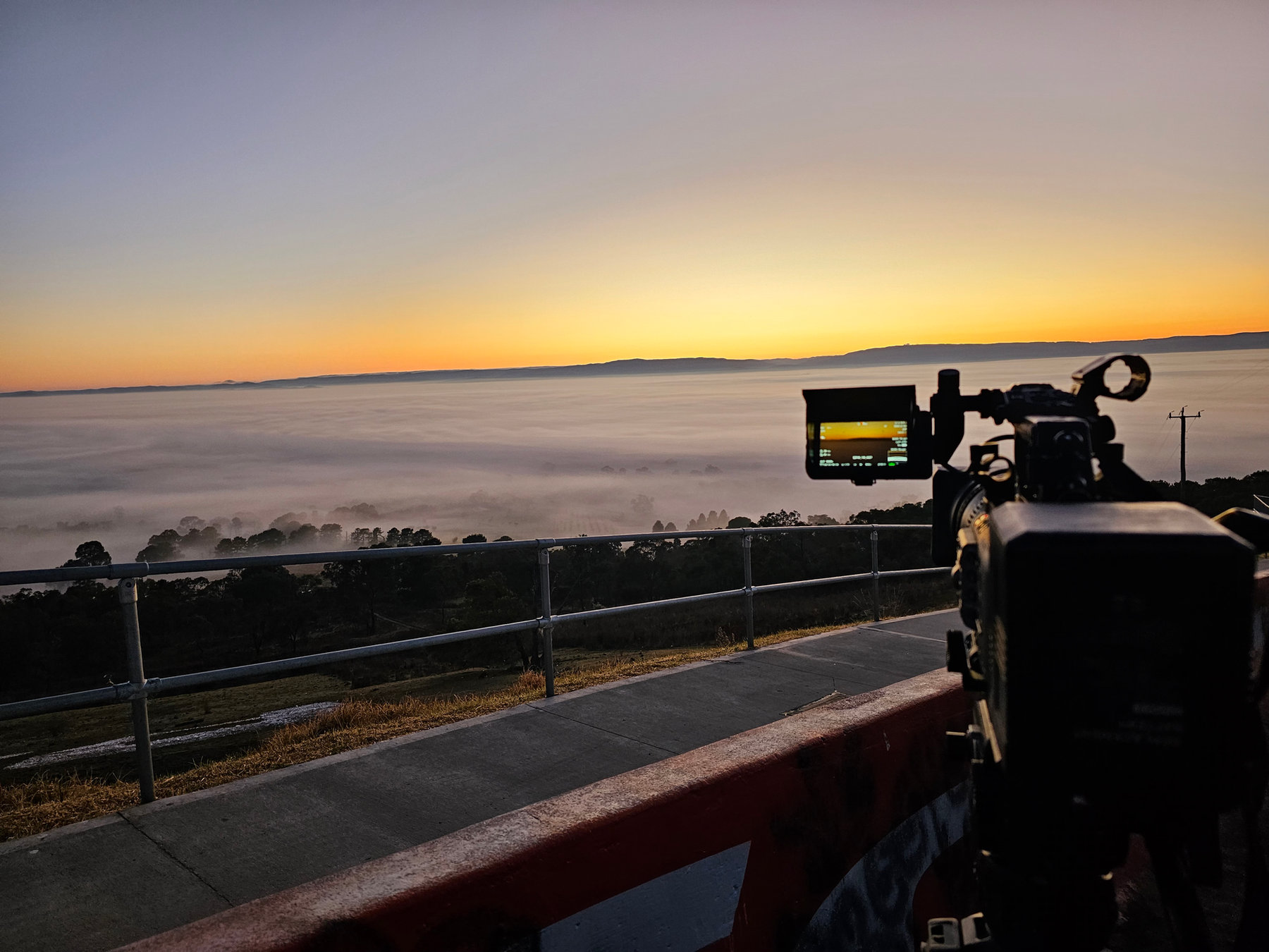 Sunrise over a valley with a camera in the foreground